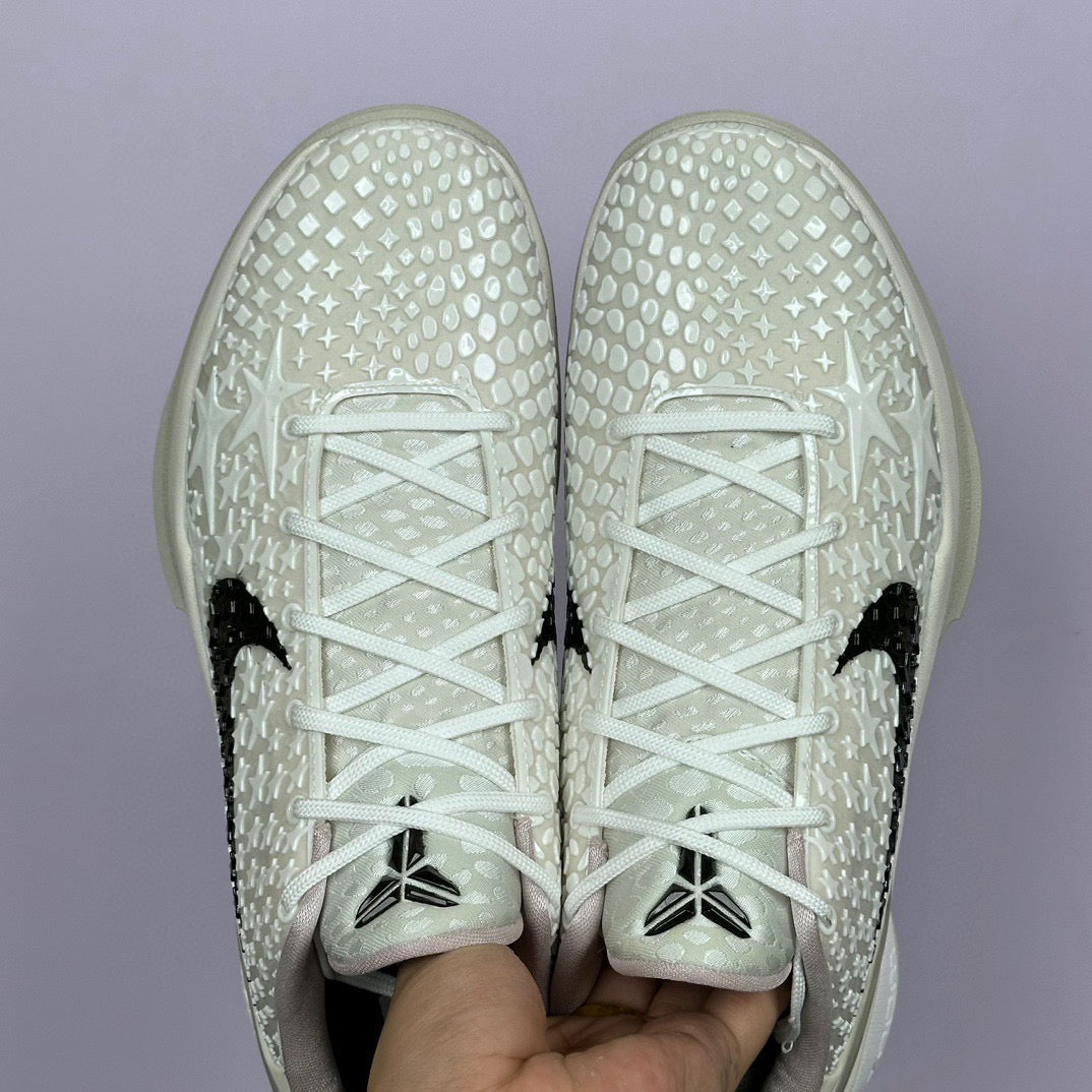 Low-top sneaker toe view, white star-pattern upper, black swoosh accents, white laces