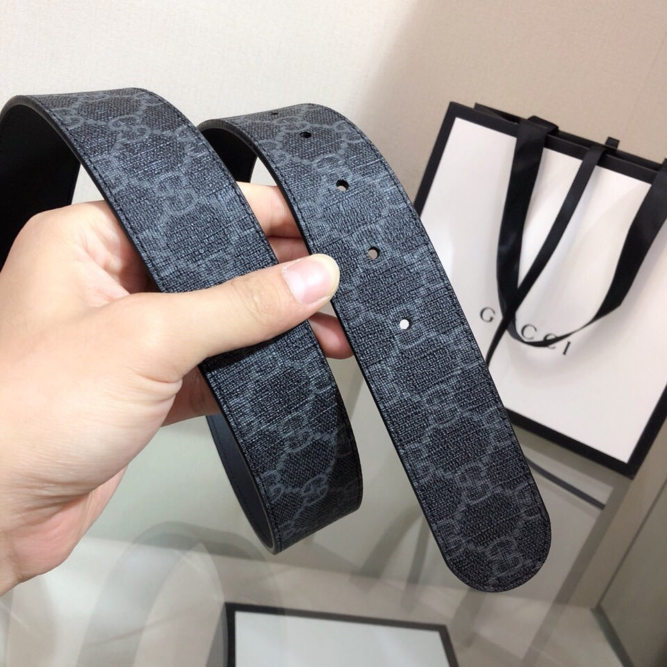 Gucci belt straps laid out with dark monogram texture and prong holes