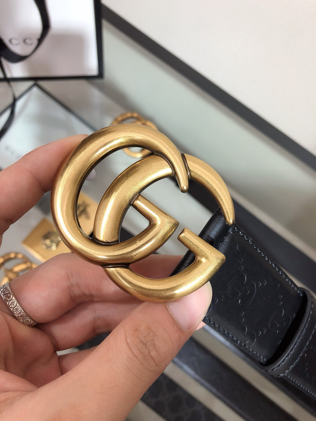 Gold double-ring buckle close-up on black embossed belt strap