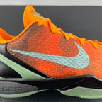 Basketball shoe side with light blue swoosh, orange upper, and green sole