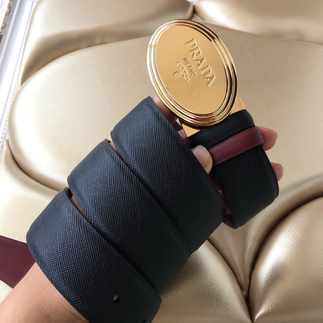 Designer belt with navy textured webbing and burgundy strap, oval gold logo buckle
