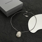Silver-tone chain necklace with round logo pendant and oval tag charm
