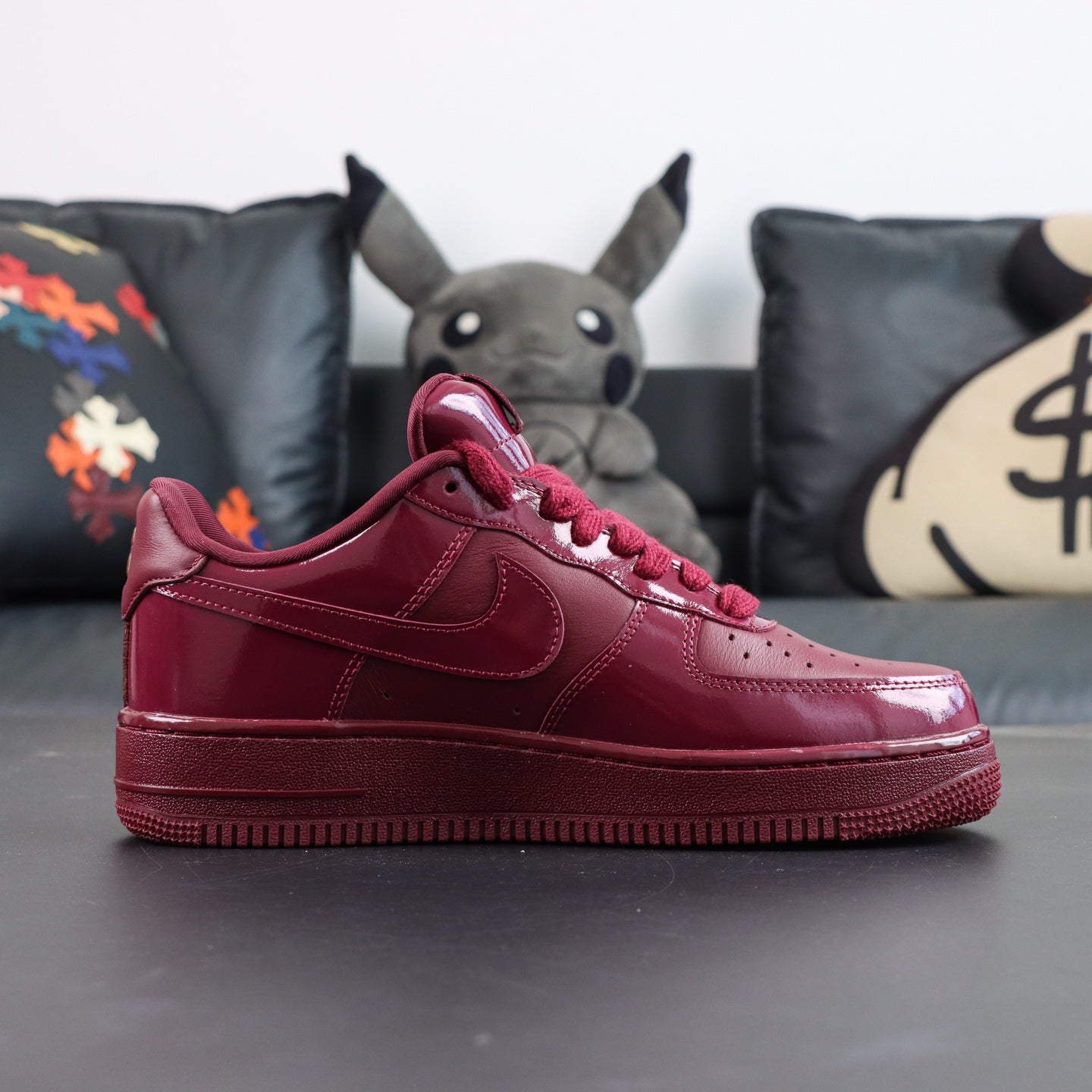 Burgundy low-top sneakers with Nike swoosh and shiny leather panels, side view