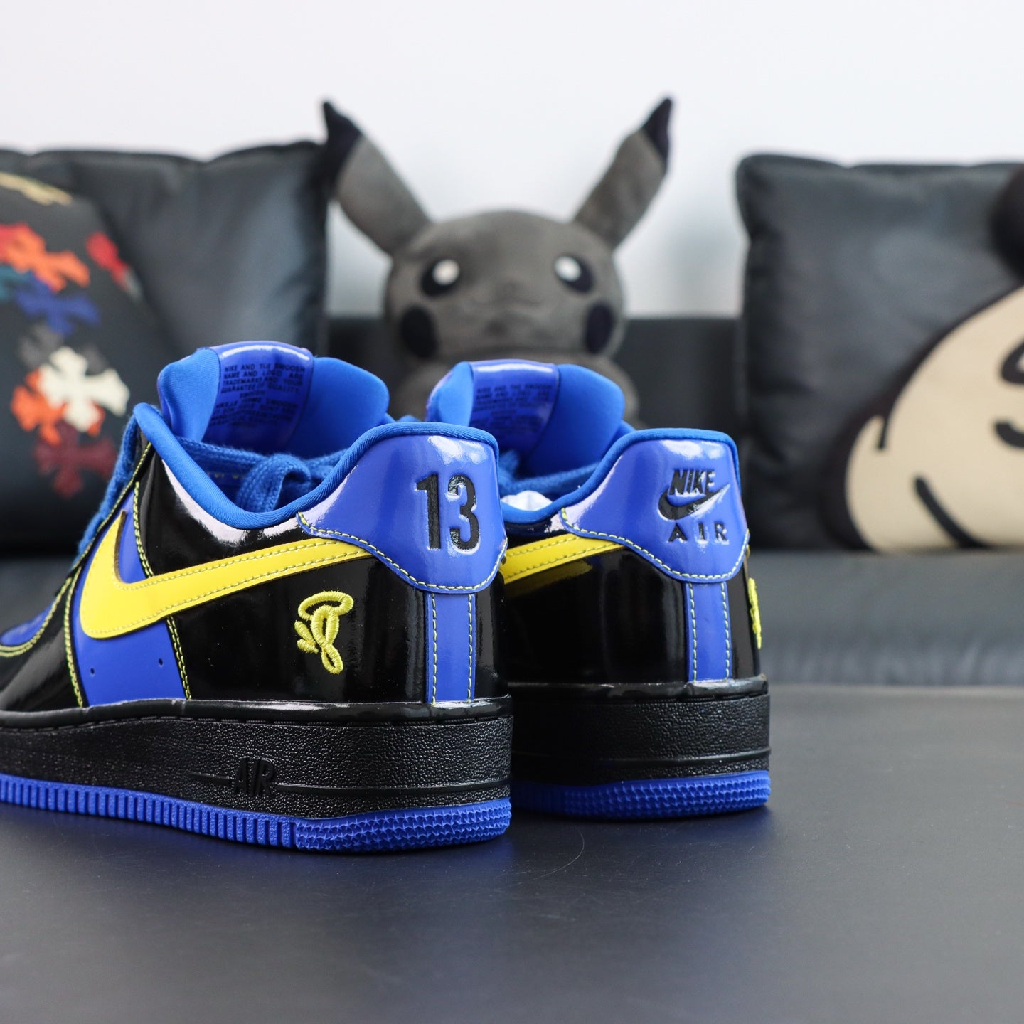 Nike Air Force 1 low-top sneakers, blue and black with yellow accents; heel detail view.