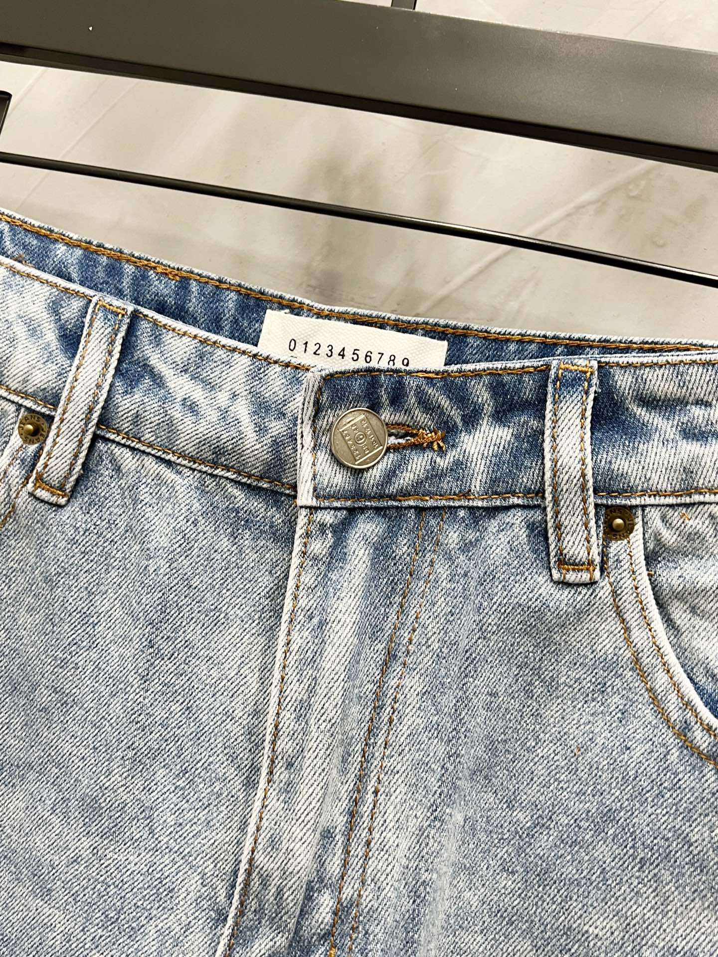 Maison Margiela denim jeans waistband close-up with engraved logo patch and belt loops