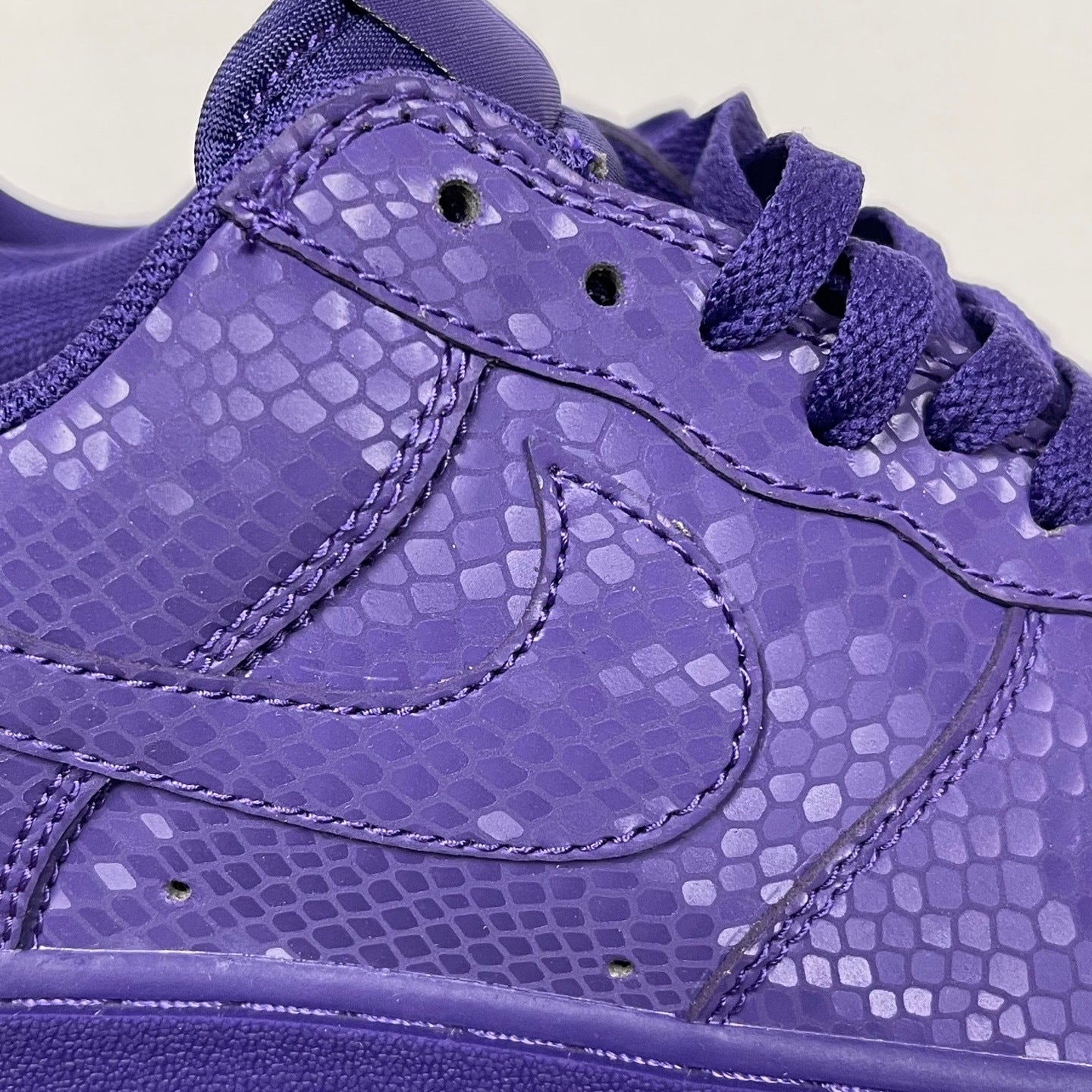 Purple low-top sneakers with lace-up closure, stitched panels, and textured finish