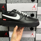 Black low-top sneaker with white swoosh and laces, side view with chunky sole