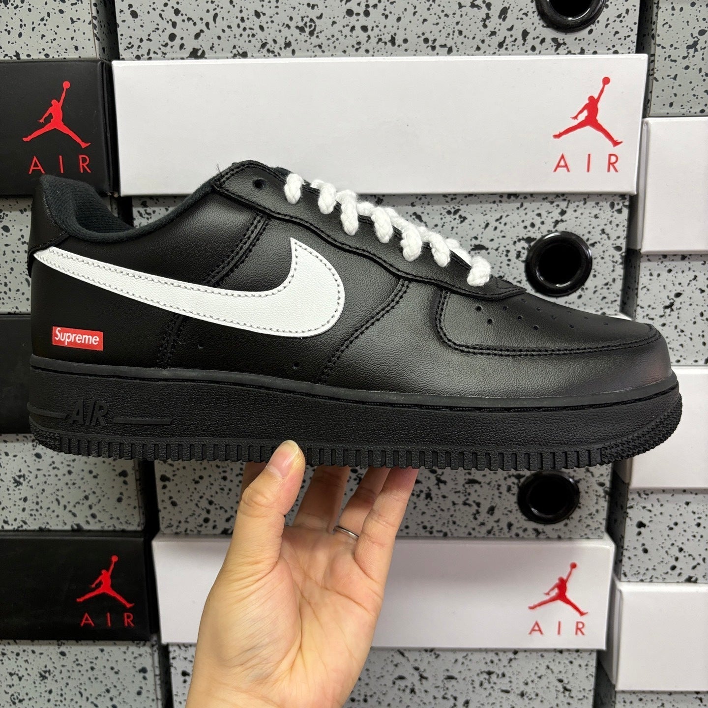 Black low-top sneaker with white swoosh and laces, side view with chunky sole