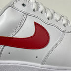 White leather sneaker with red Nike swoosh and stitched seams, lace area close-up.