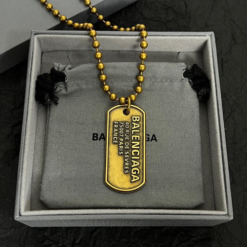 Gold-tone beaded dog tag necklace with Balenciaga pendant and engraved text