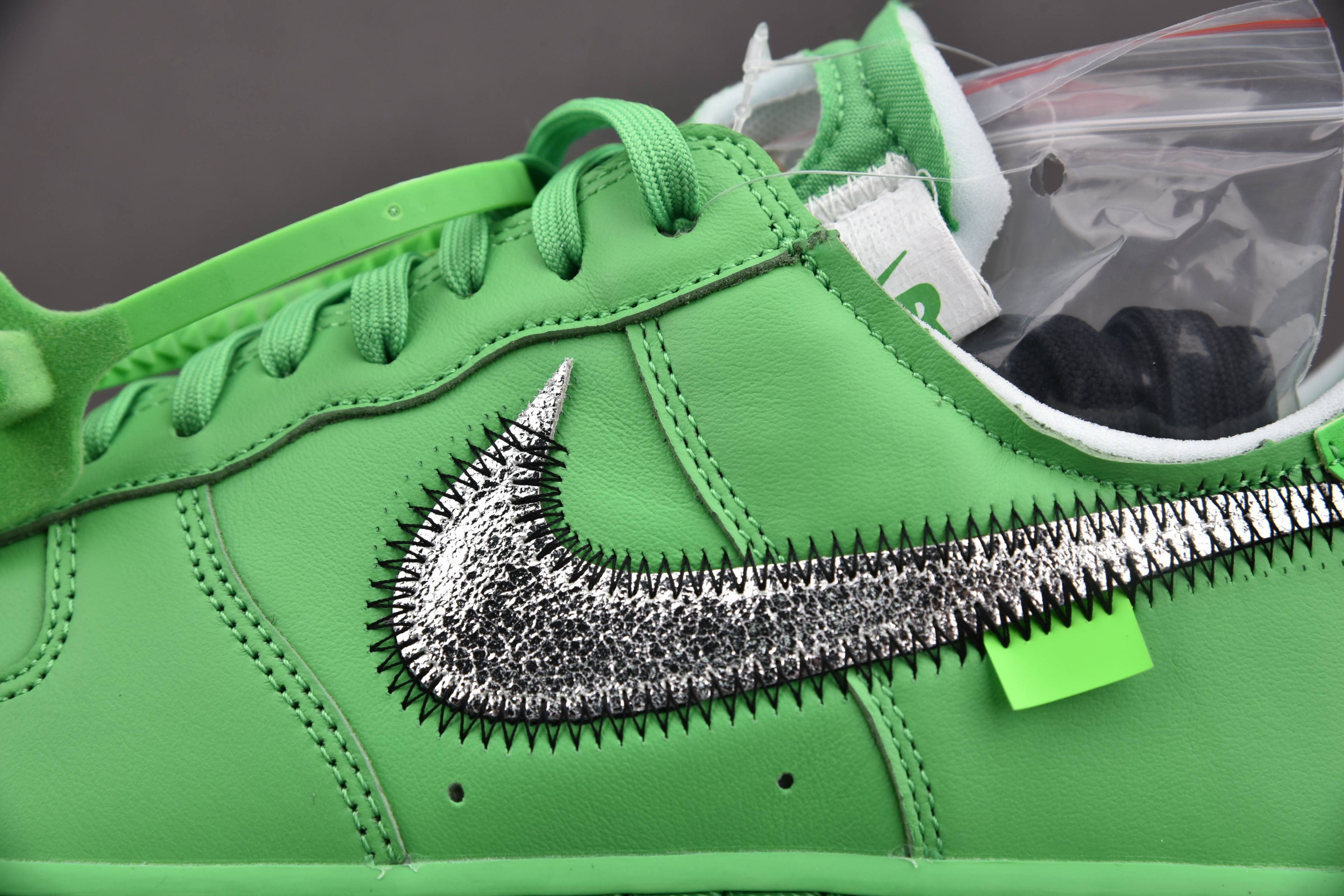 Green sneaker side panel with metallic swoosh and green laces