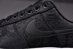 Black low-top sneakers with textured pattern, padded collar, and black Swoosh