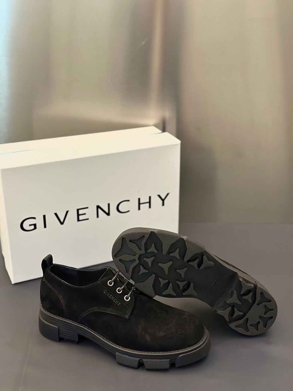 Black lace-up shoes with rugged sole tread and lace-up front.