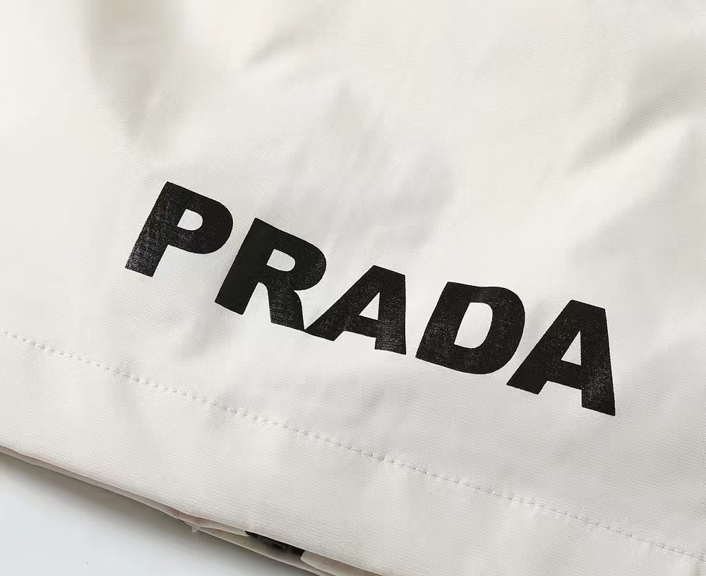 White jacket fabric close-up with large black PRADA lettering