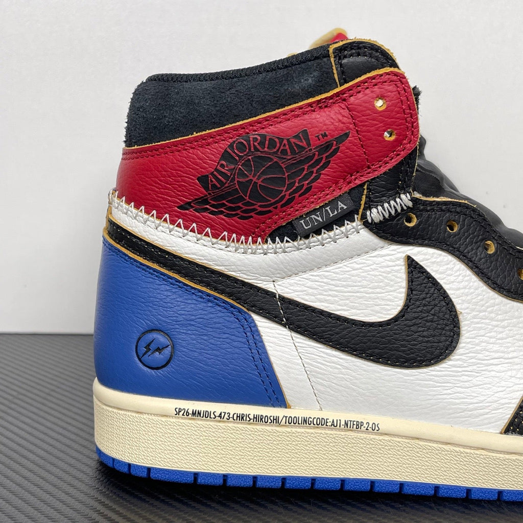 High-top sneaker side view, red ankle panel, black suede, white swoosh, blue outsole