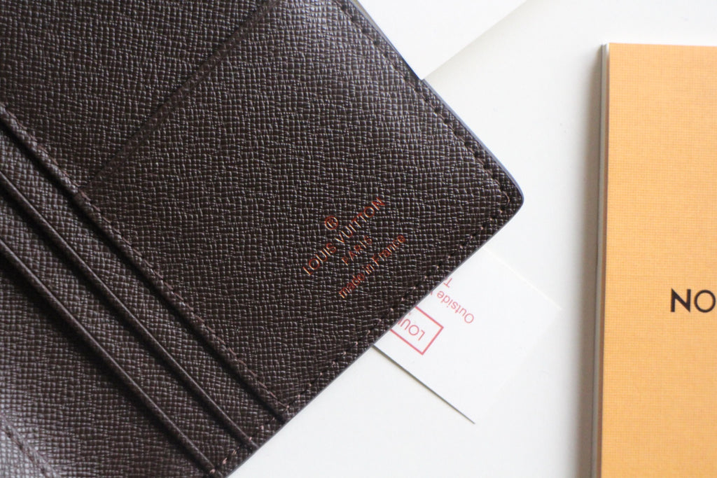Louis Vuitton small wallet front panel with embossed logo and dark textured leather