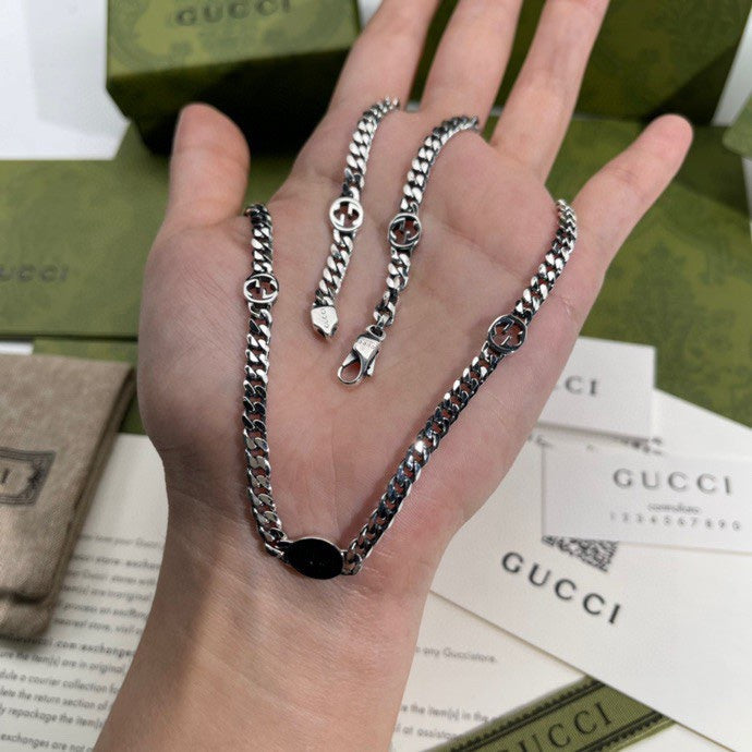 Silver-tone chain necklace on hand, multiple chain strands with round logo pendant