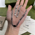Silver-tone chain necklace on hand, multiple chain strands with round logo pendant