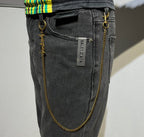 Balenciaga gold logo chain accessory on dark jeans with brand label tag