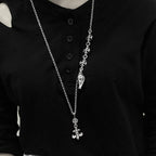 Silver chain necklace with dagger-like and cross charms over a black shirt