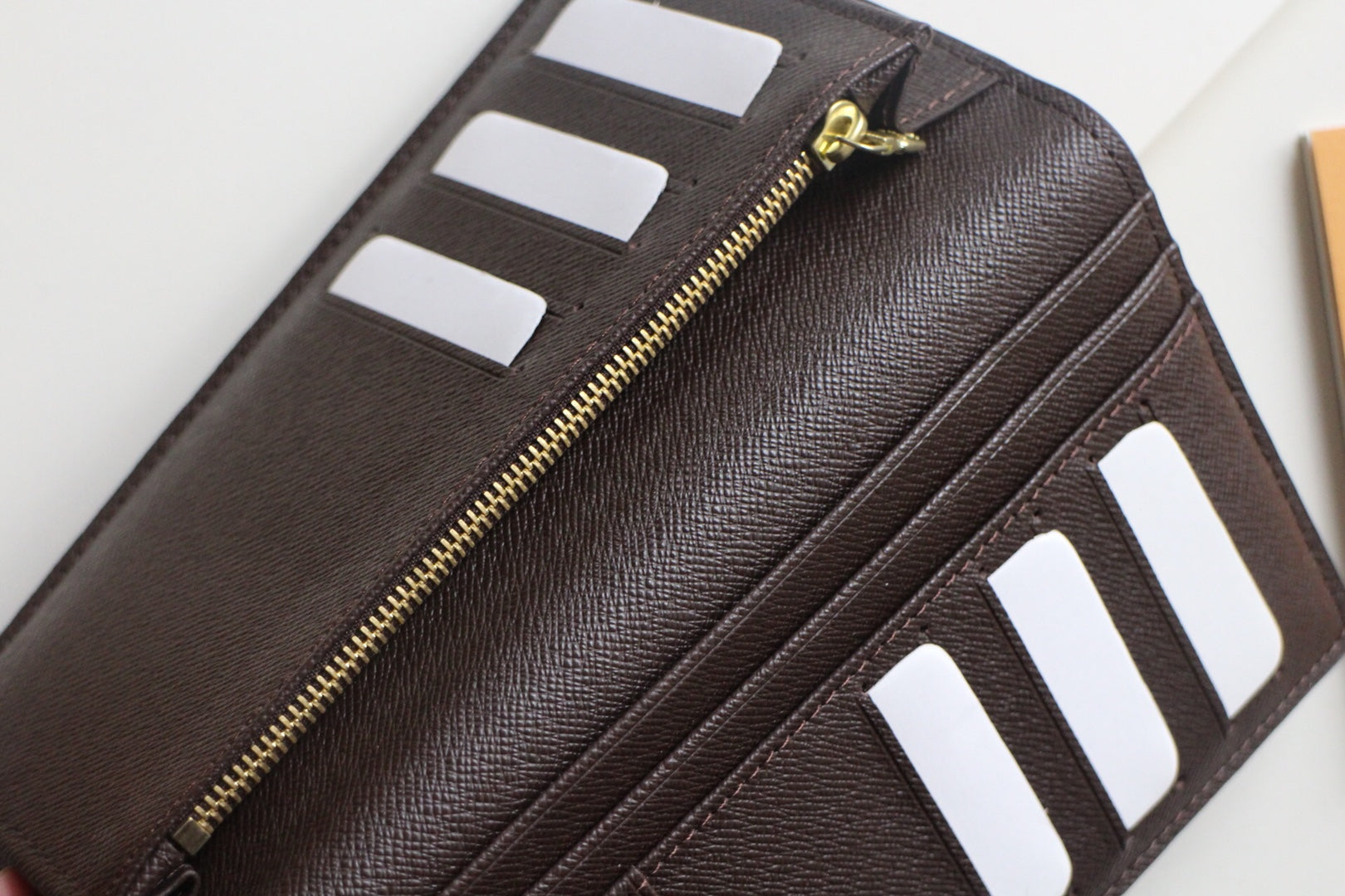 Louis Vuitton small wallet with gold zipper and card slot pockets in dark leather
