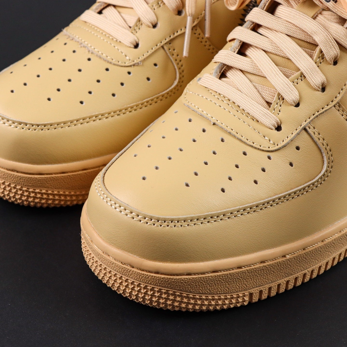 Close-up of cream Air Force 1 low-top toe with perforations and tan lace details