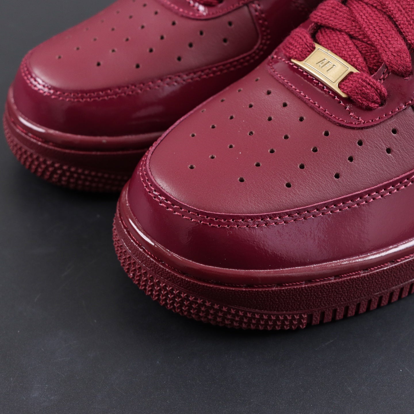 Burgundy sneaker toe box with perforations and lace eyelets, close-up