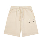 Light beige Maison Margiela shorts with elastic waistband, drawstring, and dash graphic.