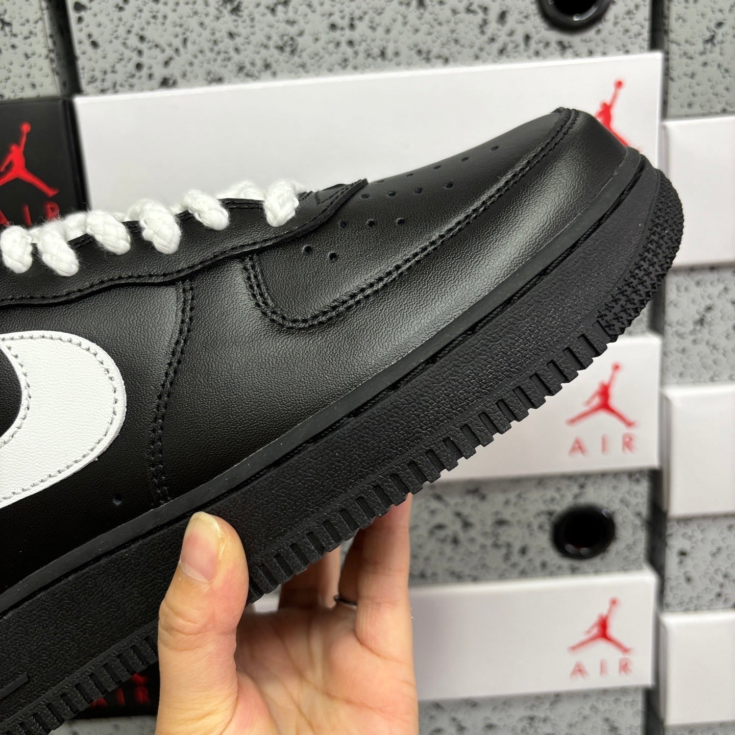Black leather sneaker side with white swoosh and textured rubber outsole