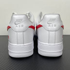 White low-top sneakers with red heel stripe and Nike AIR text on back, lace-up.