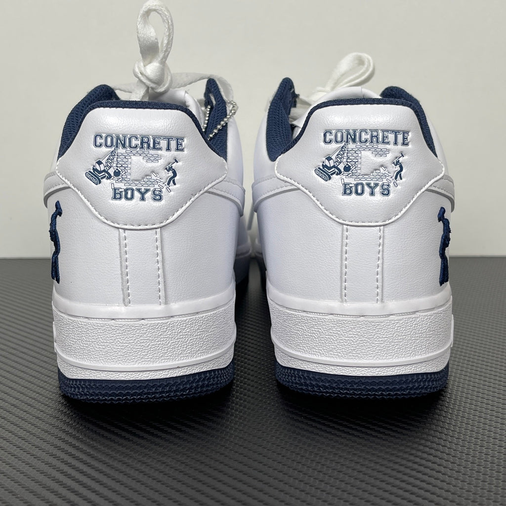 White Nike Air Force 1 heel with navy trim and “CONCRETE BOYS” text patch