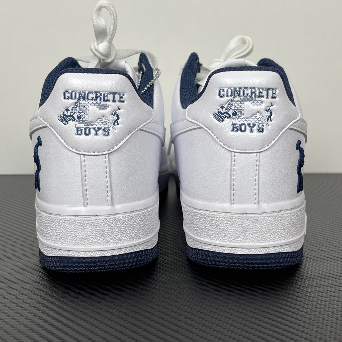 White Nike Air Force 1 heel with navy trim and “CONCRETE BOYS” text patch