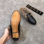 Gucci black slip-on shoe with faux fur trim and gold bit hardware, outsole shown
