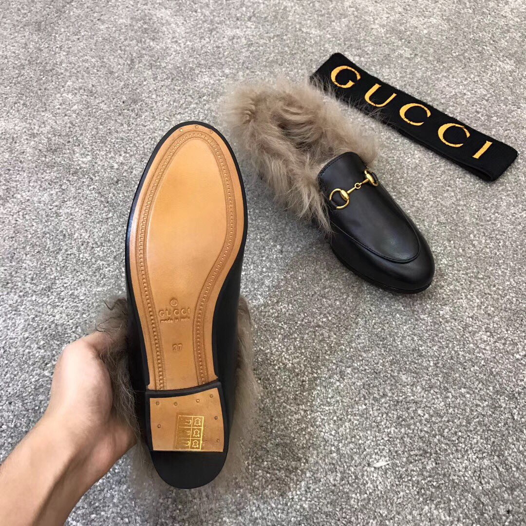 Gucci black slip-on shoe with faux fur trim and gold bit hardware, outsole shown