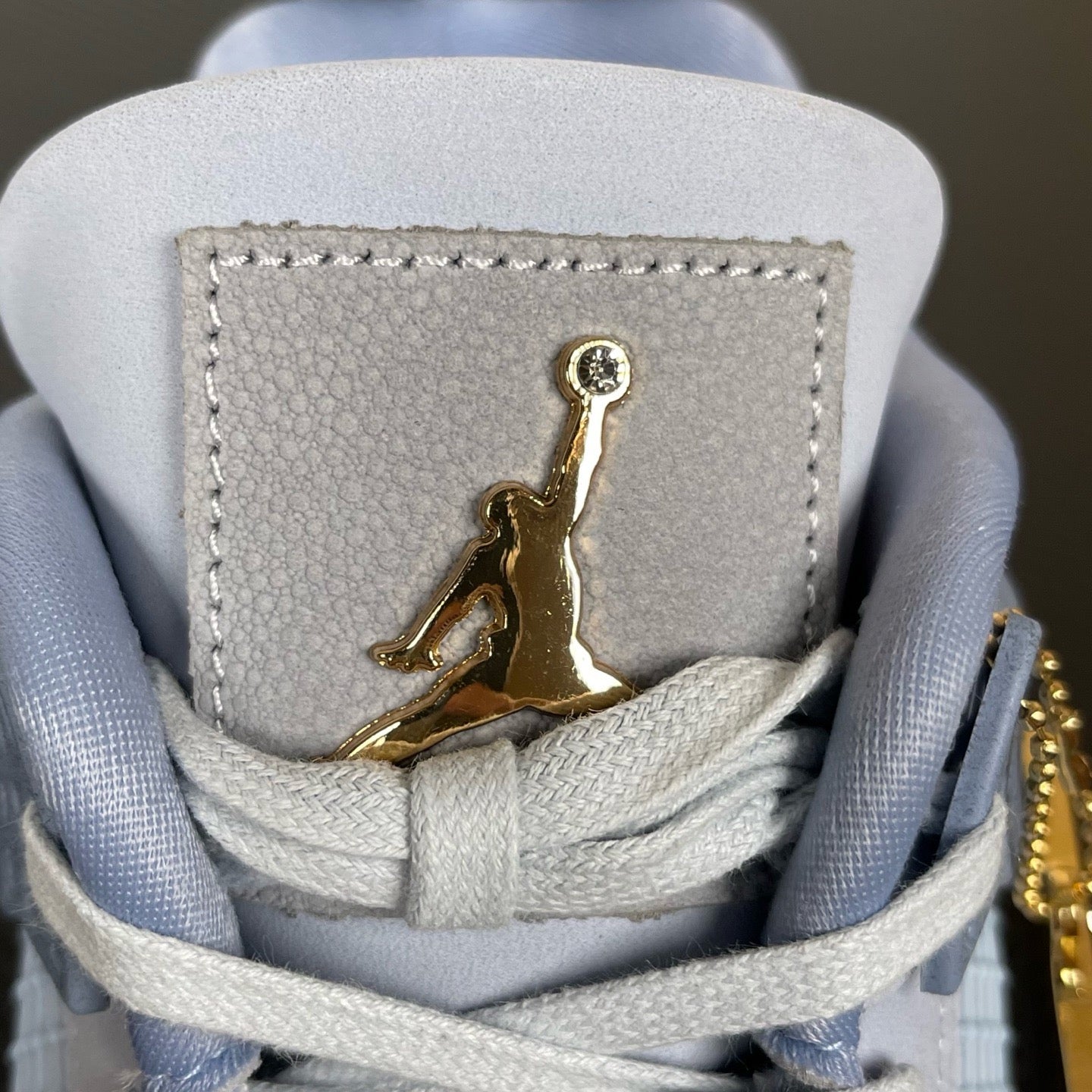 Back heel area of light blue Air Jordan 4 sneakers with gold Jumpman patch