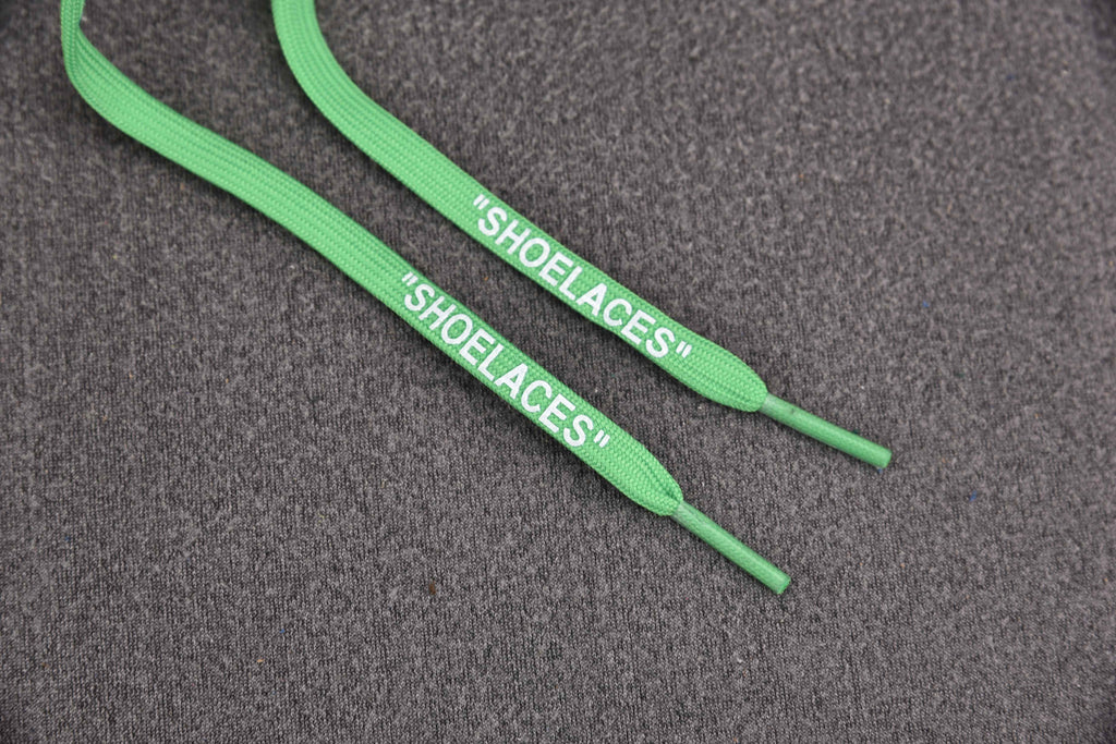 Green shoelaces labeled on gray surface