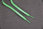 Green shoelaces labeled on gray surface