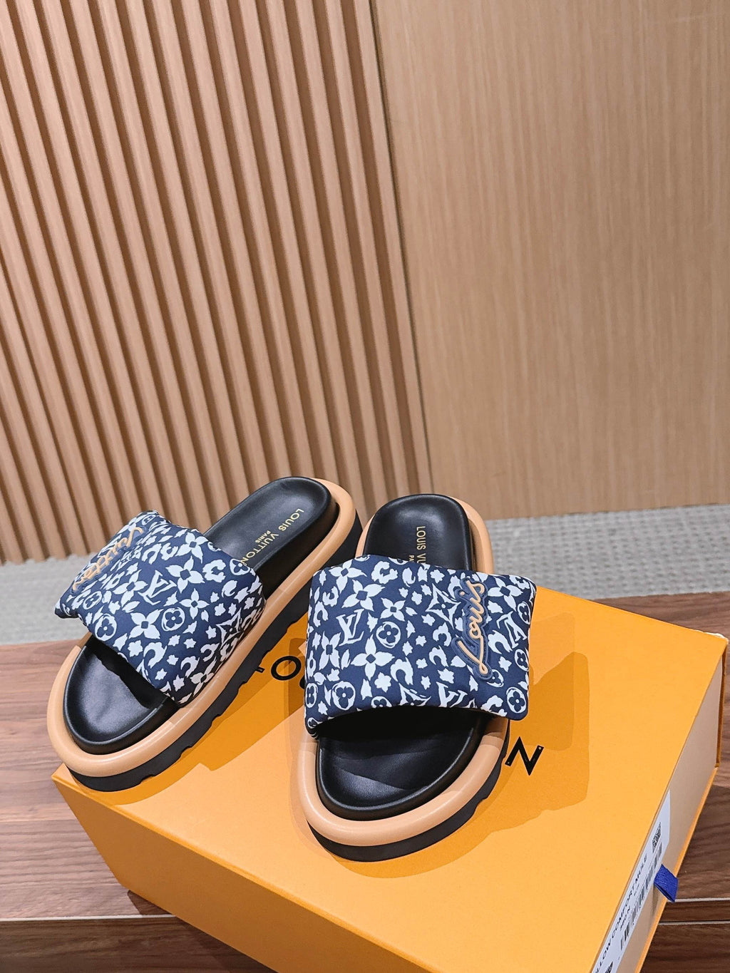 Louis Vuitton slide sandals on box: blue patterned straps, black footbeds, light tan outsoles