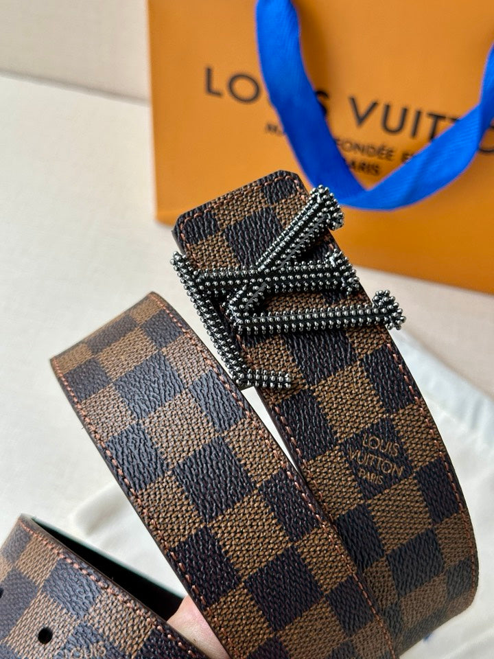 Louis Vuitton belt close-up: dark checkered strap with silver V buckle and studs