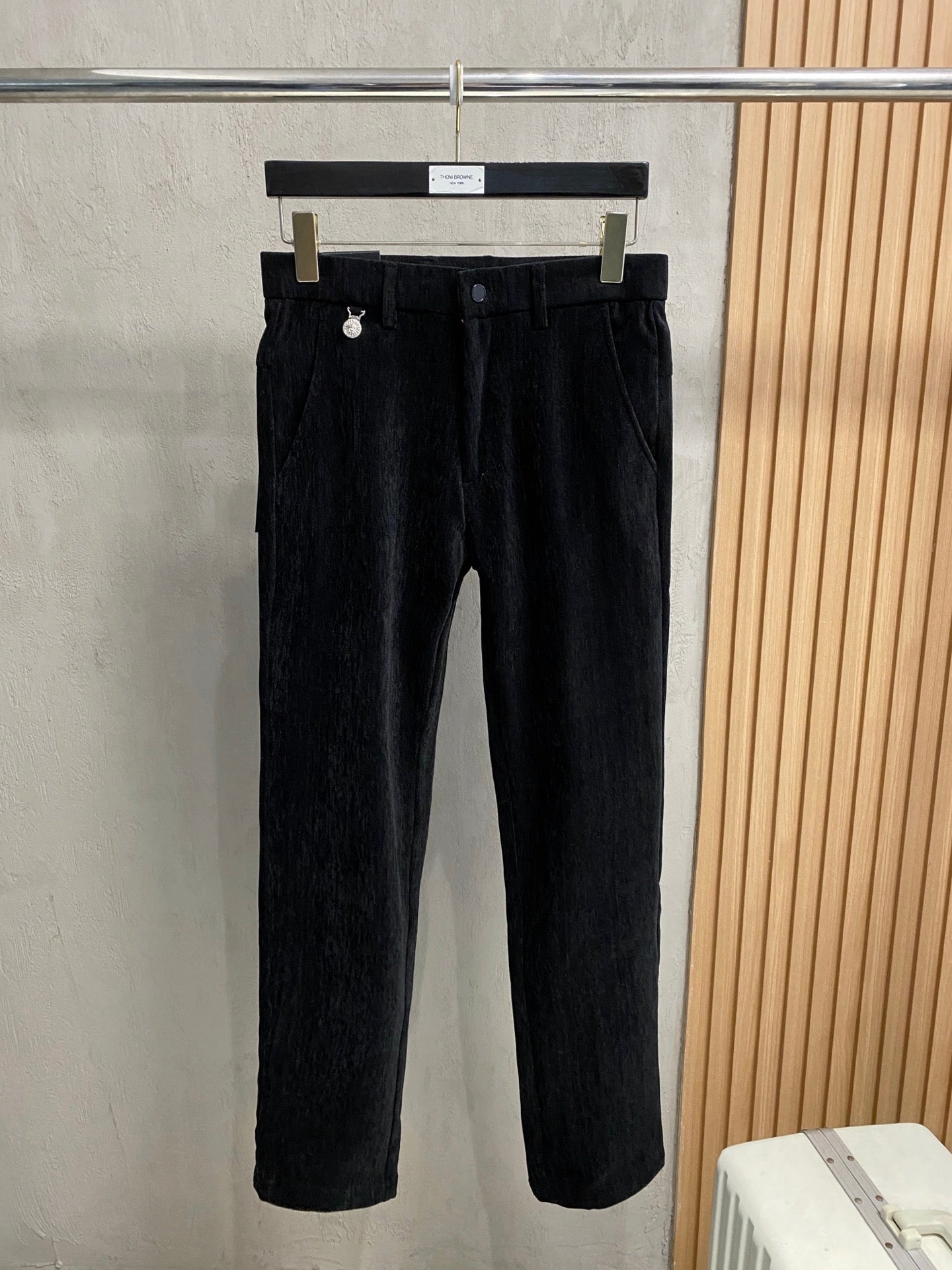 Black trousers on hanger with belt loops and button closure