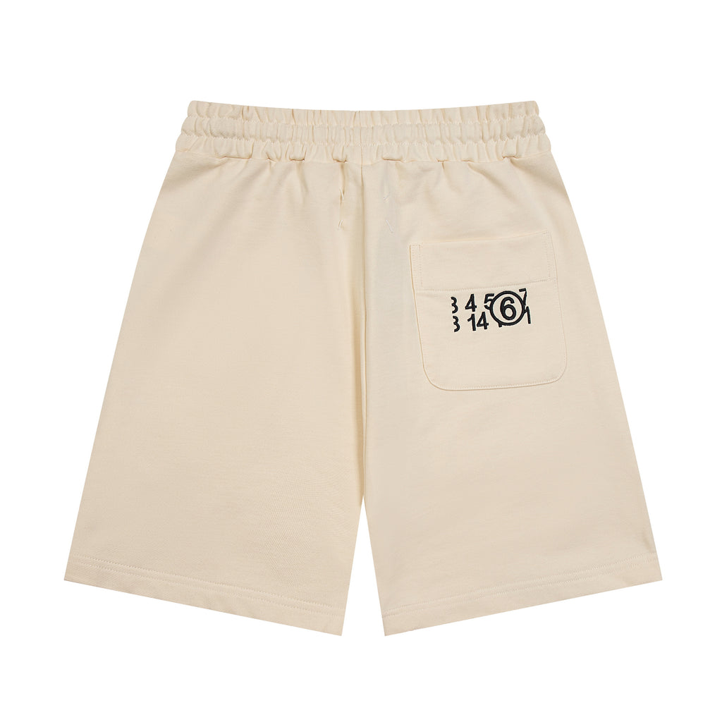 Light beige Maison Margiela shorts with drawstring and logo graphic on front pocket.
