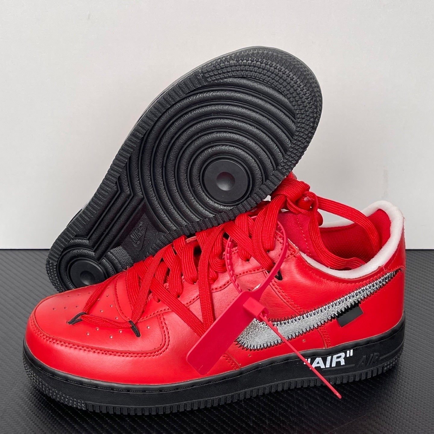 Red low-top sneakers with textured black outsole tread and silver swoosh