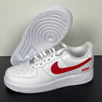 White low-top sneakers with red swoosh, outsole visible on underside, lace-up.