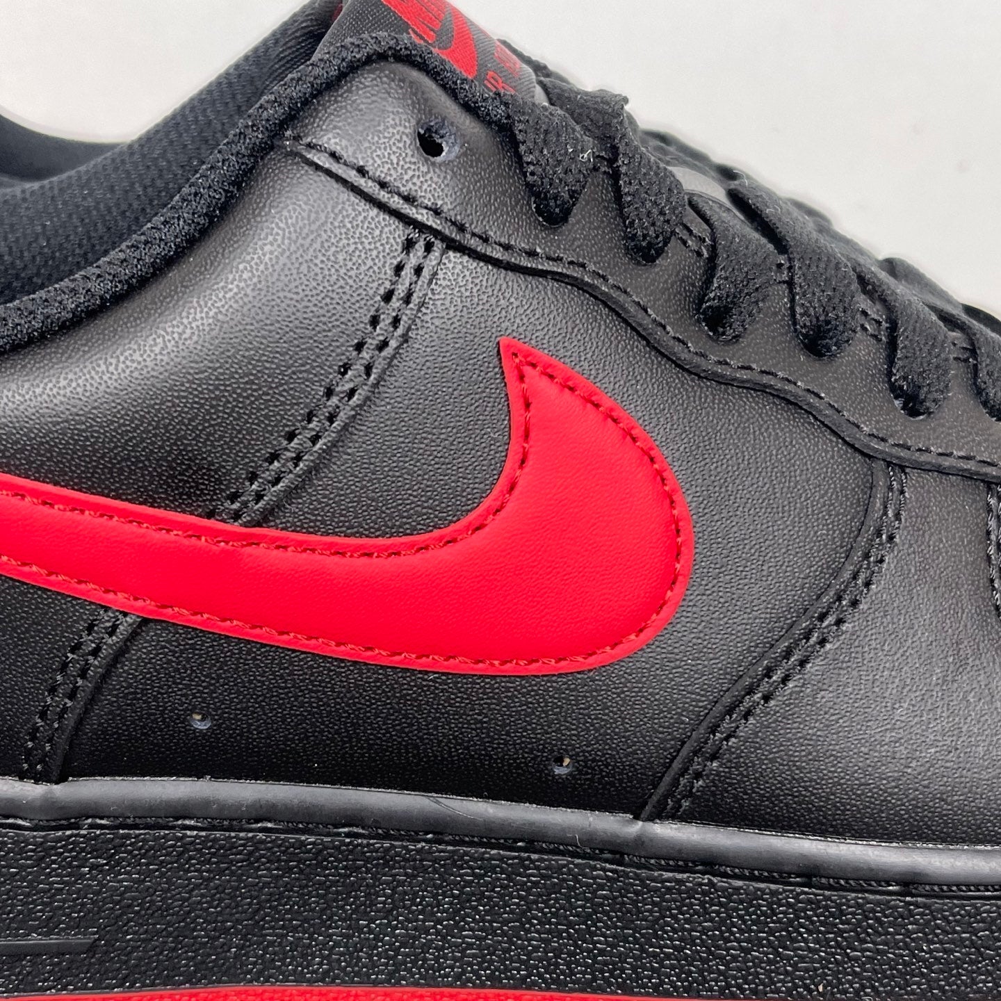 Close-up of black leather sneaker with red swoosh and black laces