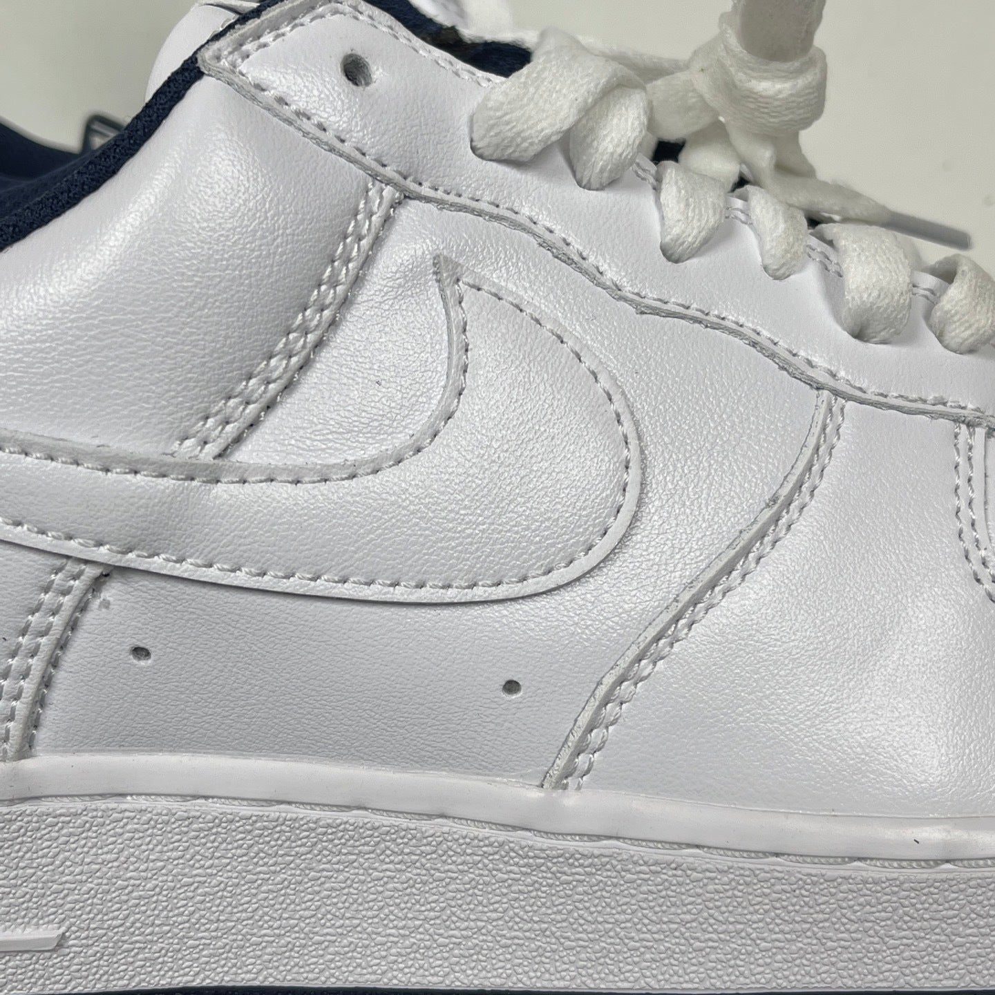 White Nike Air Force 1 side panel with stitched swoosh and lace-up collar