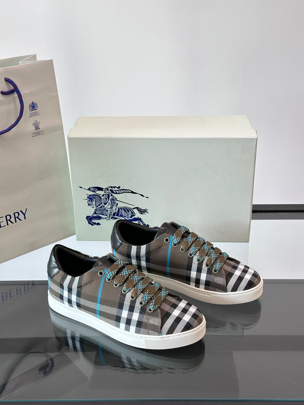 Plaid low-top sneakers pair, lace-up with black trim and blue accents on box