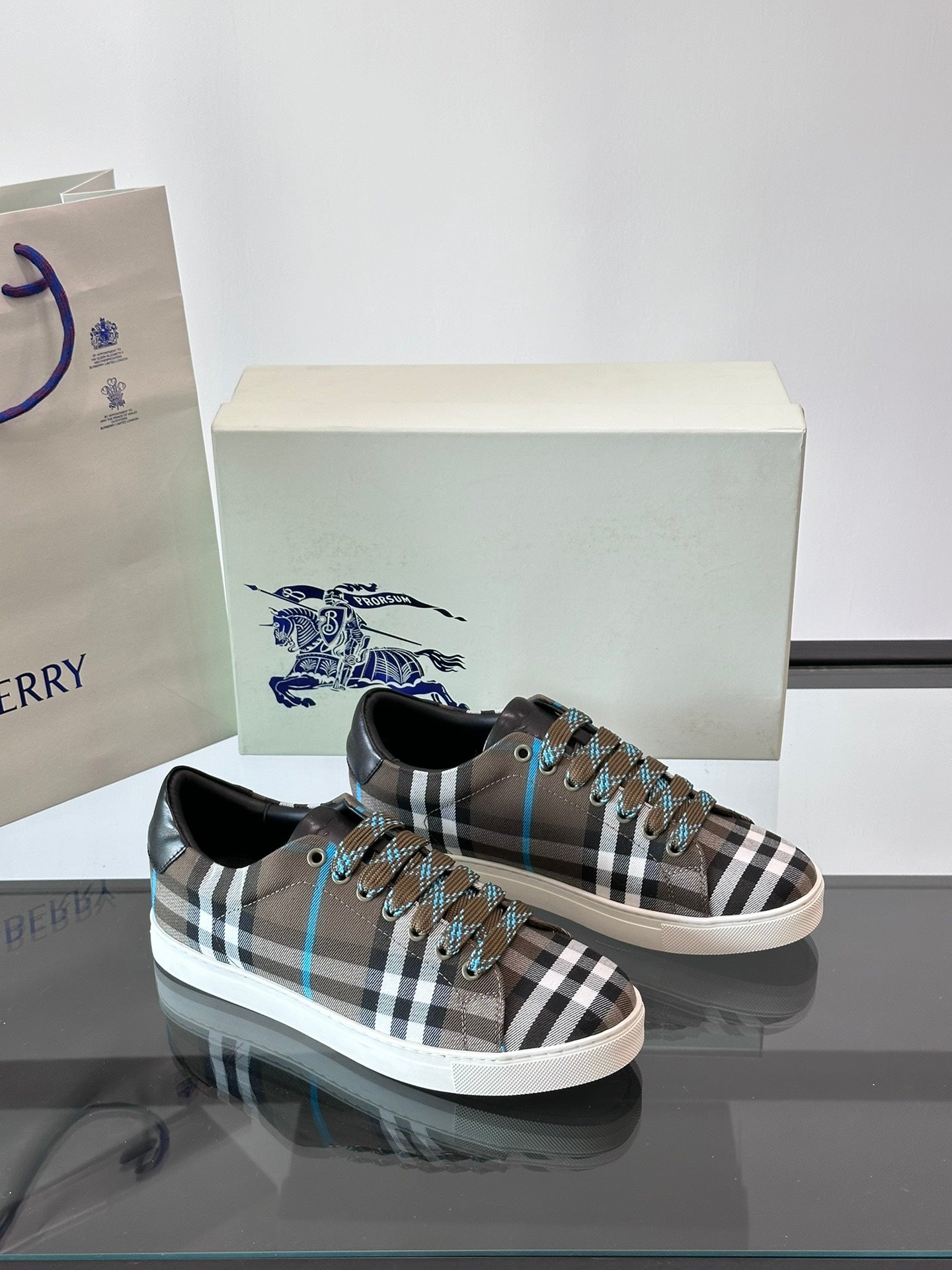 Plaid low-top sneakers pair, lace-up with black trim and blue accents on box