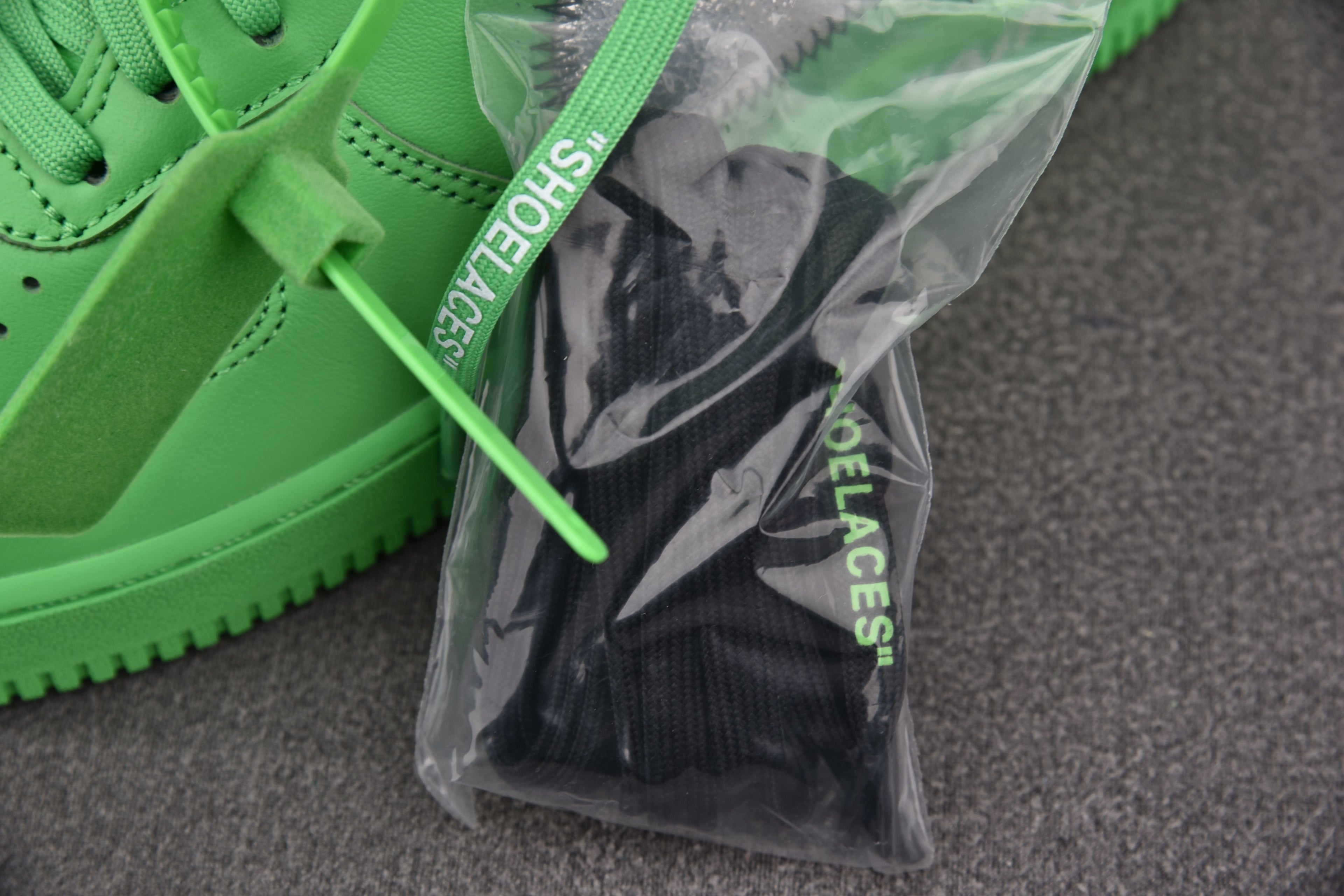 Green low-top sneakers with spare laces in clear plastic bag