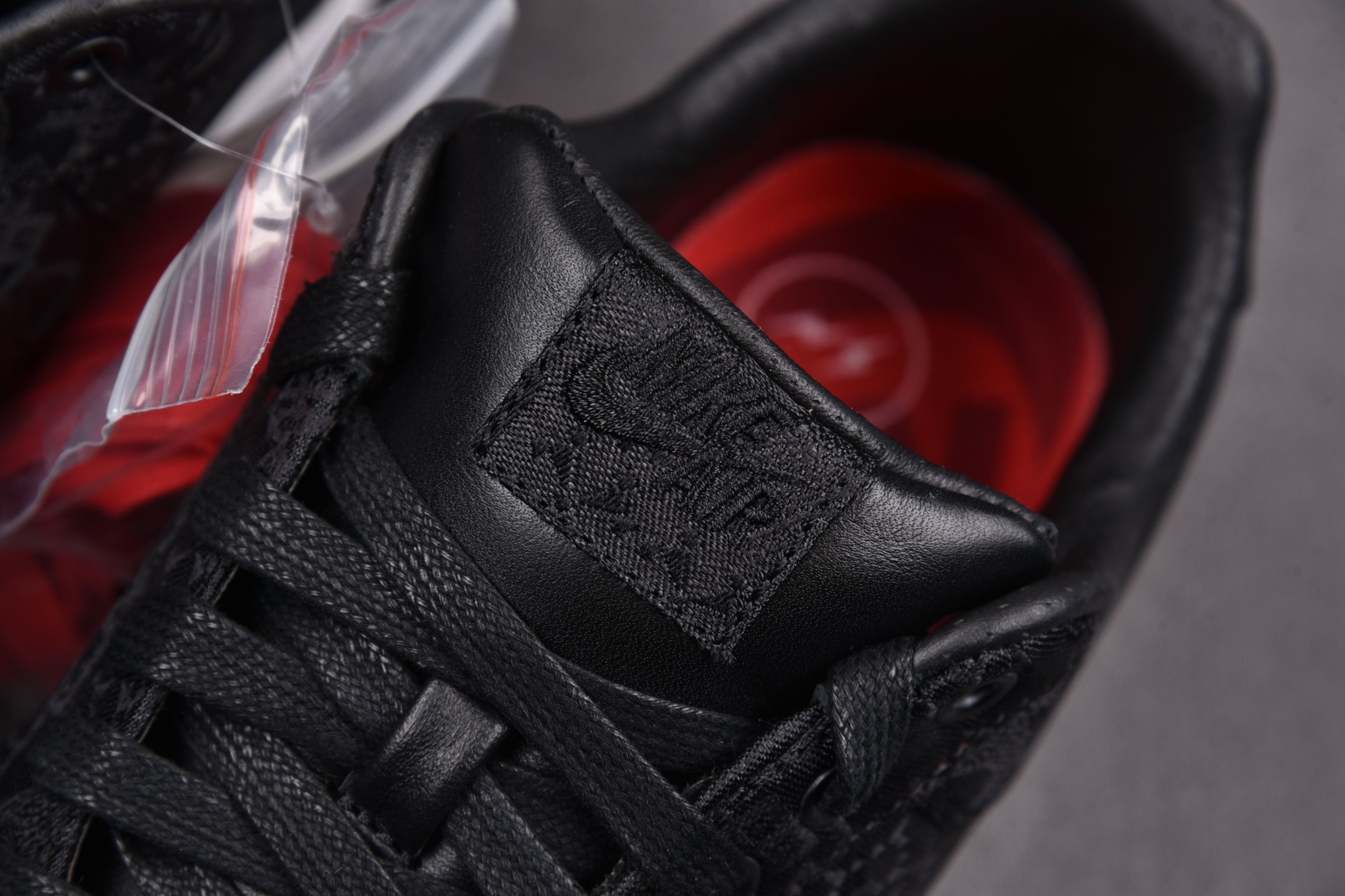 Black sneaker with laced upper and stitched strap detail