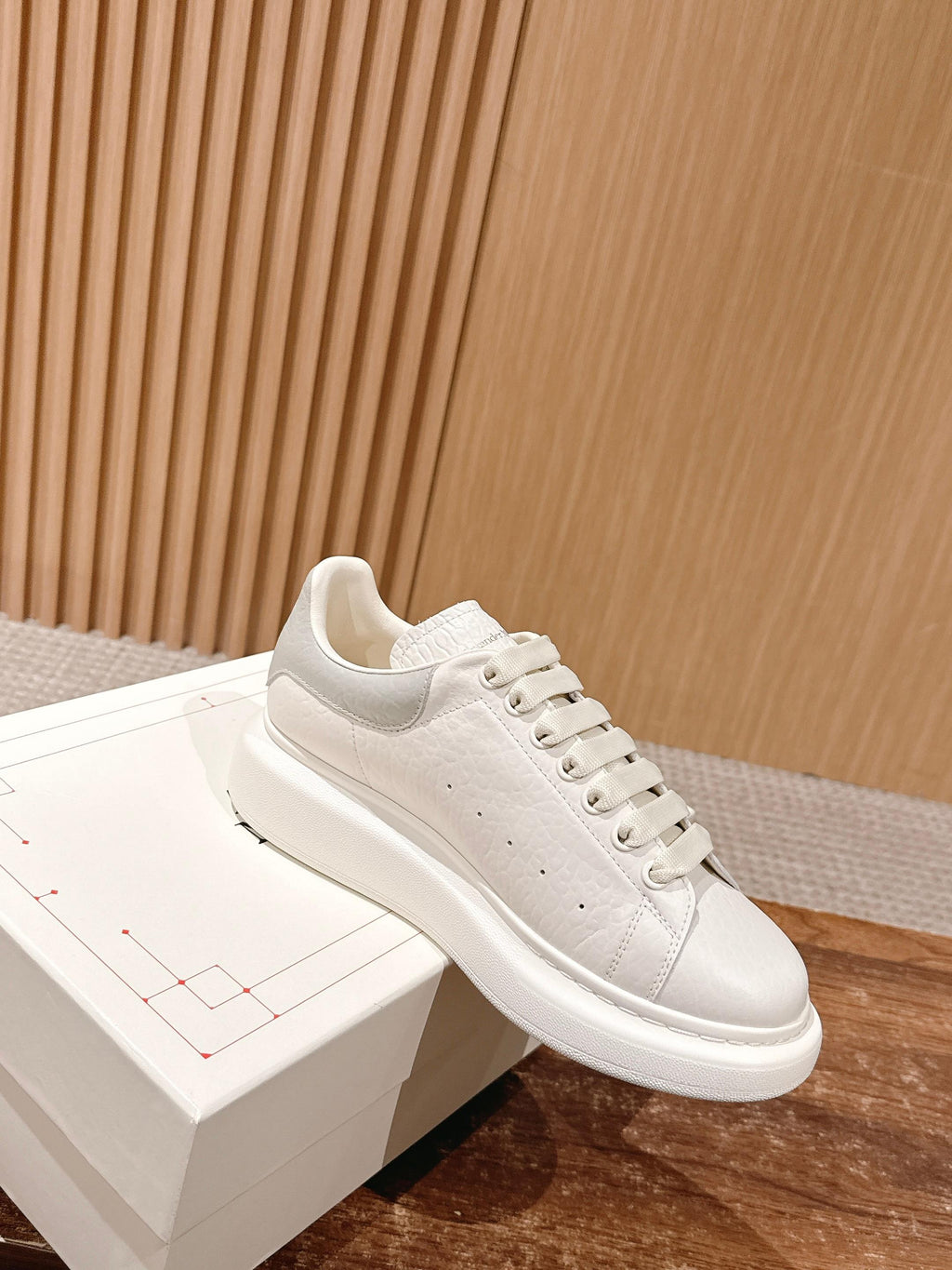 Alexander McQueen leather sneakers, white, angled side view on display box
